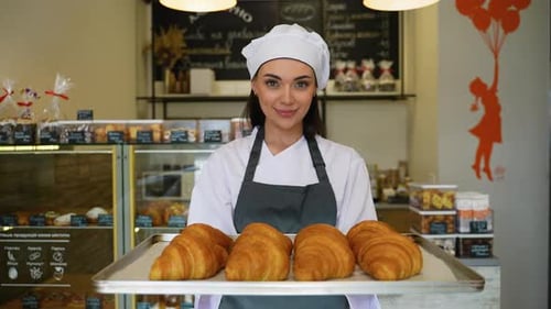 Baker Woman Holds Croissants in Cheerful Bakery
