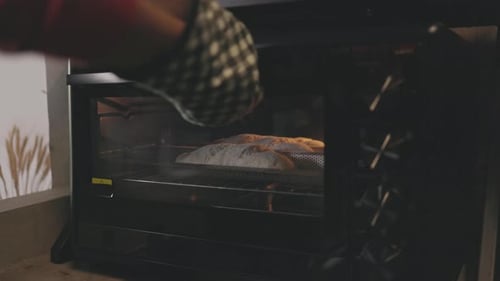 Asian baker putting dough in the oven to hand make bread