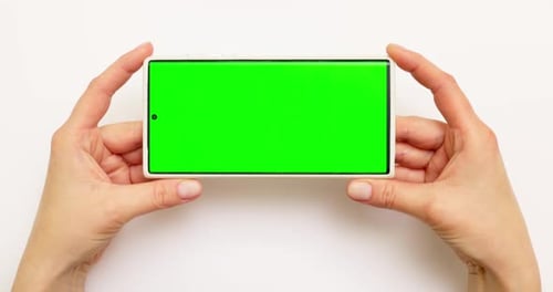 Woman's Hands Holding Smartphone with Green Screen on White Background