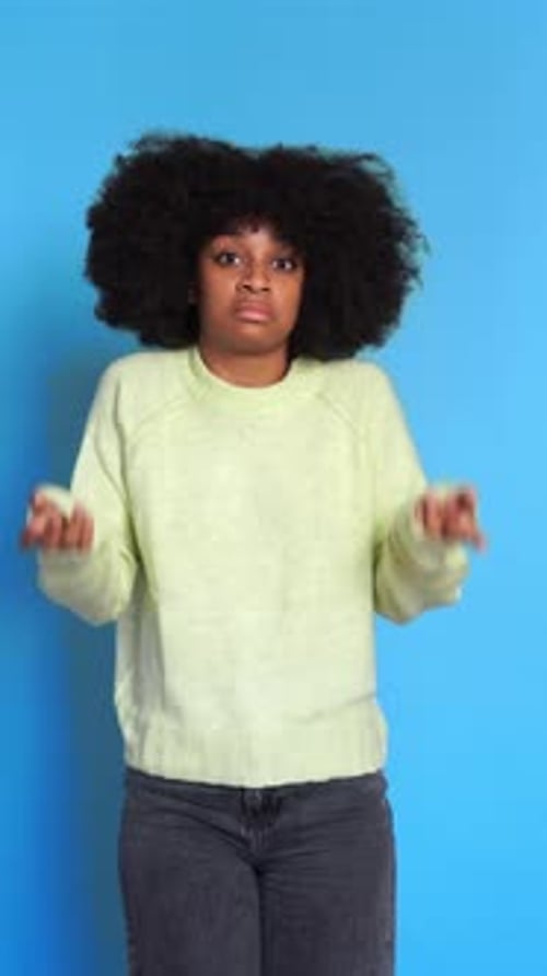 Ernsthafte schwarze Frau zeigt mit einer zweifelhaften Geste in die Kamera