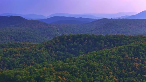 The landscape of the valley is covered with a dense forest, creating a peaceful and natural scene.