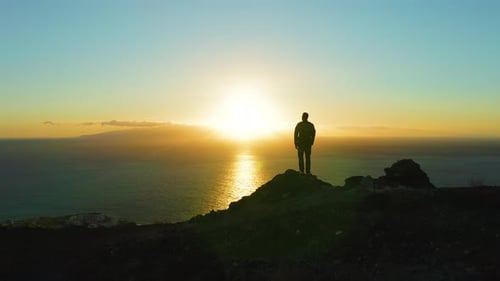 Silhouette of Hiker Man Standing on Mountain Top at Sunset