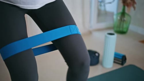 Woman Exercising Thighs Using Resistance Band Indoors