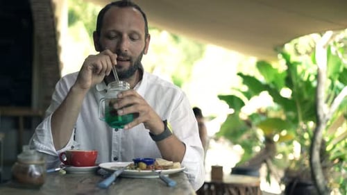 Happy, Young Man Relaxing and Drinking Cocktail Sitting in Cafe 30s
