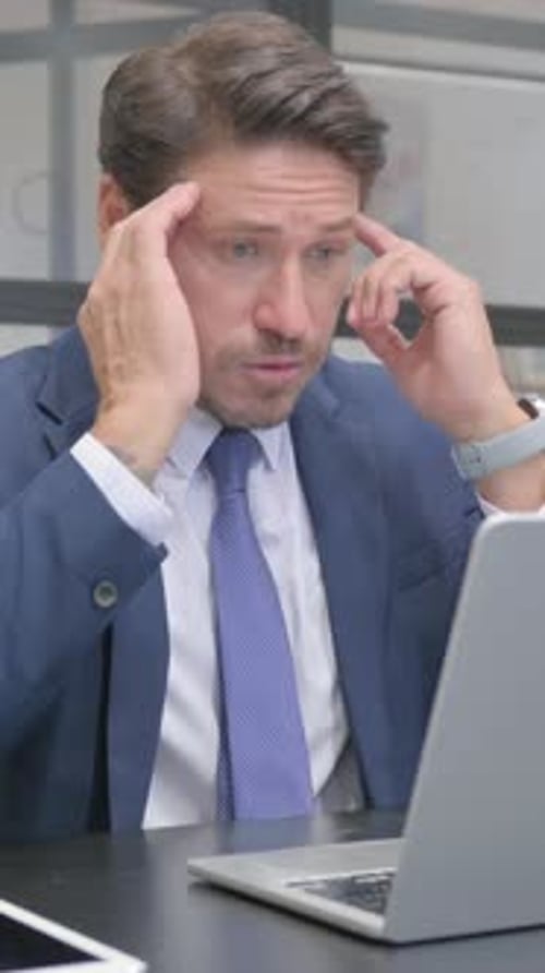 Stressed man in suit works on laptop