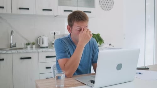 Man Working on Laptop in Bright Modern Kitchen