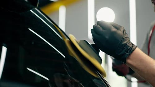 Close Up Car Detailing at a Service Station Black Car is Covered with Yellow Tape the Process of