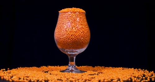 Glass of Vibrant Orange Lentils on Black Background