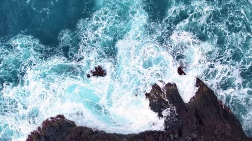 Las olas chocan contra rocas escarpadas en un pintoresco lugar costero durante el día
