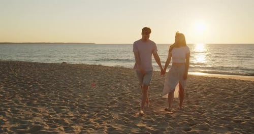 Young Loving Couple Enjoying Relaxing Sunset Walk on the Beach