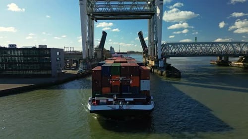 Aerial view of a fully loaded cargo ship navigating through the drawbridge and city canal of Dordrec