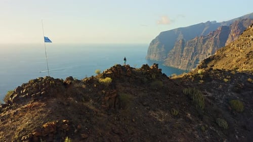 Hiker Man Standing on Mountain Top with Ocean View at Sunset