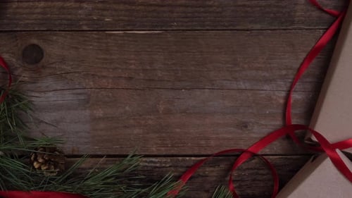 Hands Placing a Holiday Gift on Wood Table