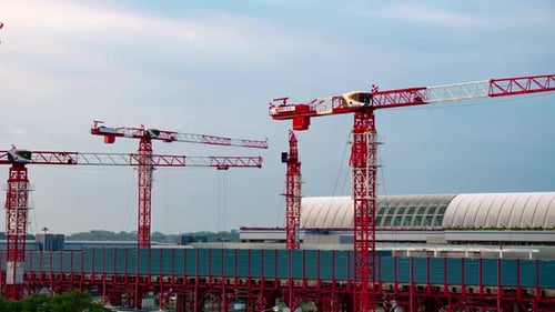 Construction Cranes Against Modern Building on Sunny Day