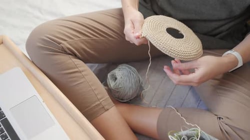 Woman Crocheting Indoors with Yarn and Laptop