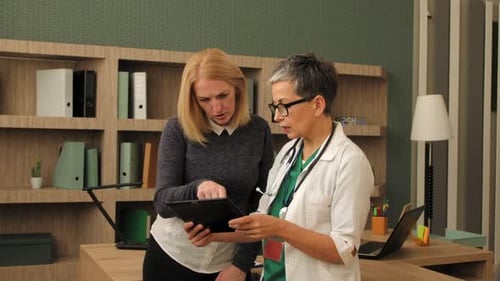 Doctor Reviews Tablet with Patient in Office