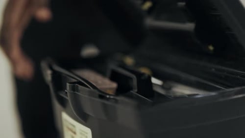 Werkzeugkiste zum Entsperren von Black Man Hands aus nächster Nähe. Mann, Arbeiter, der mit den Händen eine Schraube nimmt