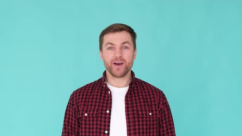 Portrait of a Handsome Smiling Young Man Looking Surprised at the Camera in a Colorful Studio