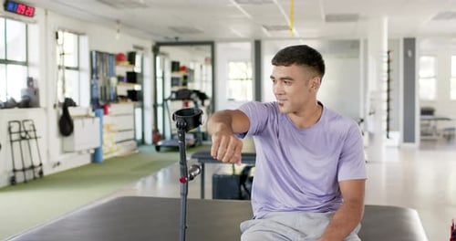 Man in rehabilitation center sitting with crutches, smiling and looking content