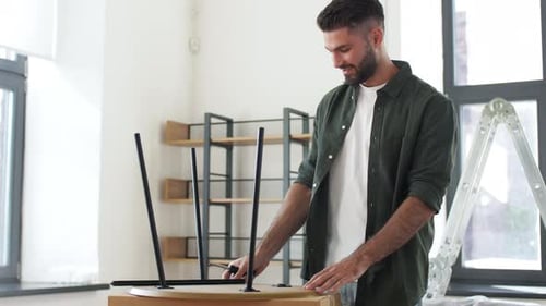 Man assembling table with screwdriver in modern home