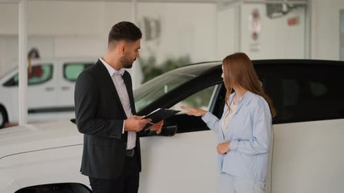 Car Salesman Explains Features to Woman in Showroom