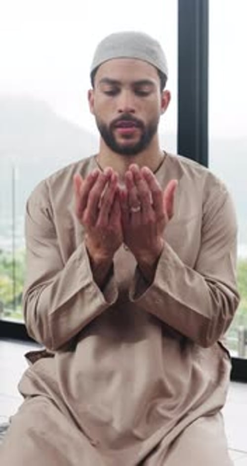 Young Man Praying Indoors in Traditional Clothing