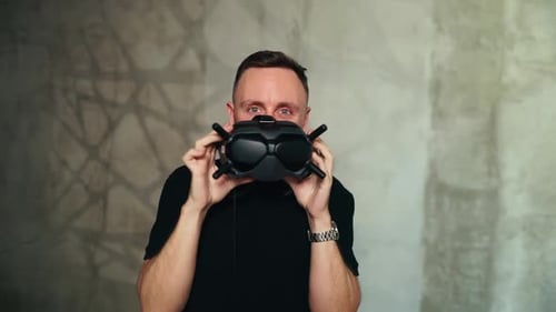 FPV Drone Pilot Holds and Adjusts Modern FPV Goggles Indoors