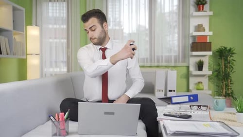 Man Works on Laptop, Sprays Cologne on Self