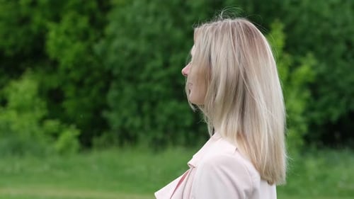 Woman with Blonde Hair Turns Head Near Trees
