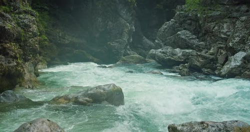 Verdunstung über einem kalten Gebirgsfluss mit klarem Wasser in einer felsigen Schlucht. Sommerliche Naturlandschaft.