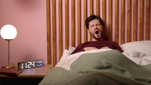 Man Wakes up and Stretches in Bed