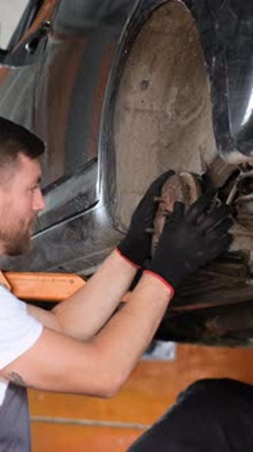 A Mechanic Diligently Working on the Underbody Maintenance of a Car in a Workshop Setting