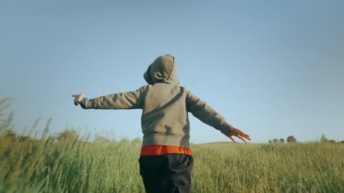 A Child Runs Through the Green Grass on a Sunny Day View From the Back