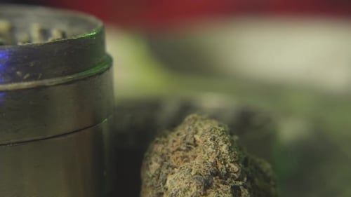 panning shot from a cannabis or marijuana bud to a weed grinder used for making the reefer fine enou