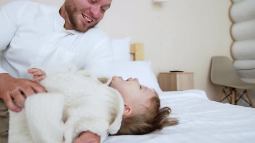 Loving Father Plays with Child on Bed