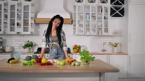 Woman Smiles in Kitchen with Fruits and Vegetables