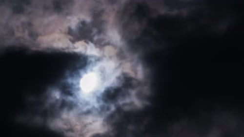 Full Moon Shines Through Clouds in Night Sky