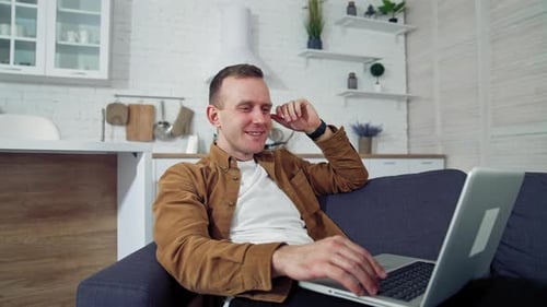 Man Relaxes on Sofa Using Laptop at Home