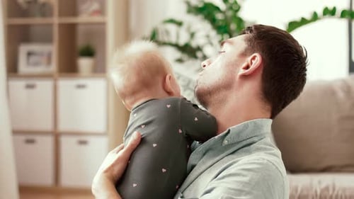 Loving Father Cradling Adorable Baby Indoors