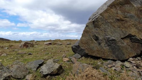 Huge boulder on stony grass mountain top time lapse rising as rain storm weather passes
