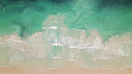 Aerial view of sea waves rolling onto tropical sandy beach with turquoise water