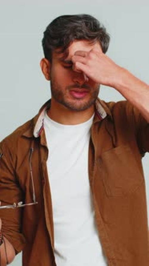Man Takes Off Glasses and Rubs Eyes in Discomfort