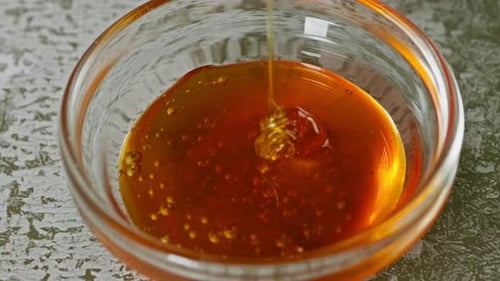 Sweet Honey Is Poured Into Glass Cup On Table