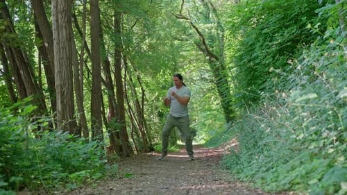 A Person Practices Martial Arts Techniques While Walking Along a Peaceful Wooded Path A Man Engages