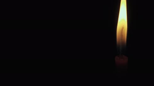 Red candle on a black background, in motion, slider shot, extinguish a candle, smoke from a candle,