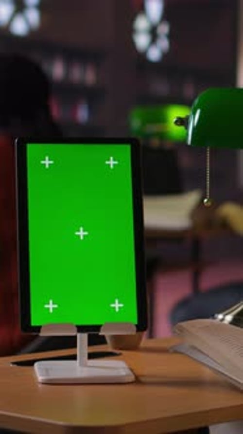 Vertical Video Schoolgirl Reading a Book Next to Copy Space on Tablet at the Library Desk