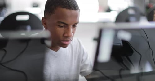 Closeup teenage boy using a computer in class