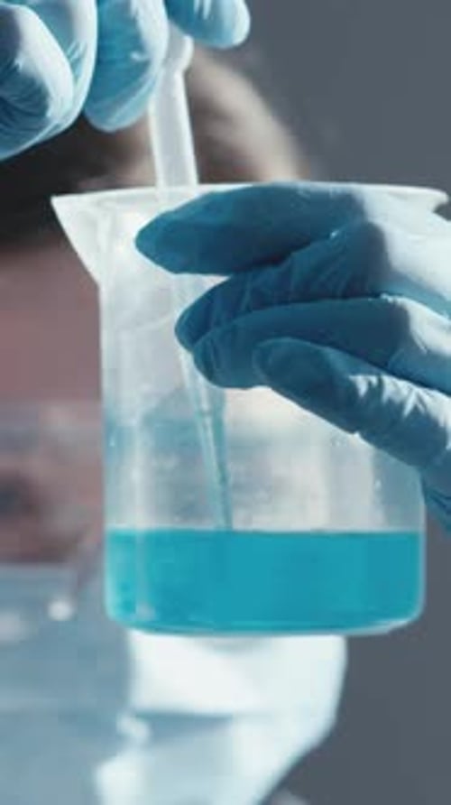 Un chercheur assidu mène une expérience détaillée avec un liquide bleu vif dans un tube à essai