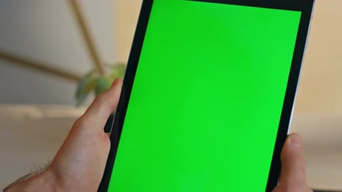 Man Holds Tablet With Green Screen Indoors