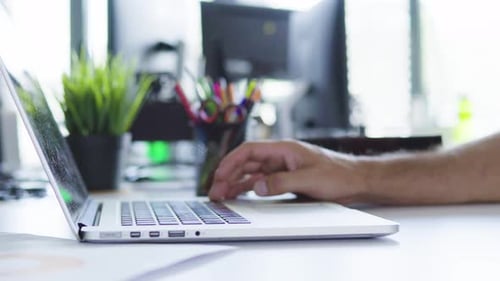 Unrecognizable businessman typing on laptop in sunny office environment